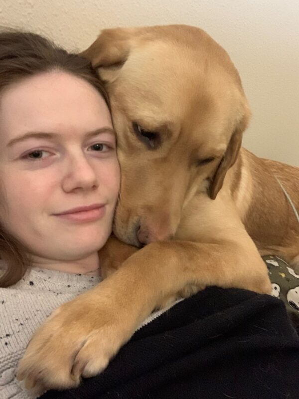 Up close selfie of Meerkat cuddling with his trainer. Their faces are pressed together which enhances Meerkat's wrinkles.