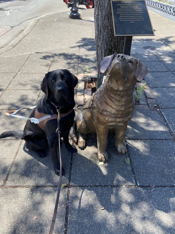 Nura sits in harness next to the famous Gresham statue of GDB guide